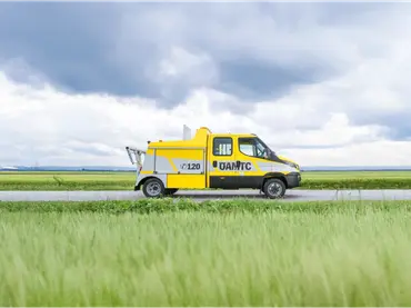 ÖAMTC roadside assistance vehicle driving through rural landscape, highlighting mobile breakdown service and in-vehicle technology